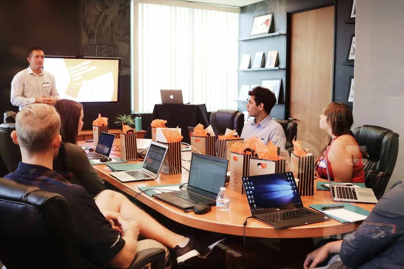 A founder presenting to colleagues around a boardroom table, illustrating the company control USCIS looks for when your own company sponsors your O-1 visa